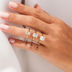 a woman's hand with three different rings on her fingers and one has an engagement ring