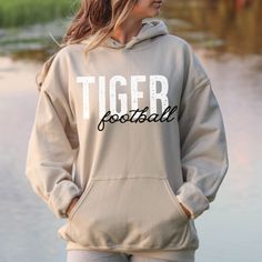 This is the perfect school spirit hoodie!  This tigers football pullover is great for all the football games! This vintage Tiger Football design is perfect on the popular Gildan brand hoodie. This vintage style hoodie will keep you warm throughout the autumn season!  A pre-shrunk, classic fit hoodie that's made with air-jet spun yarn for a soft feel and reduced pilling. ** P R O D U C T **  - 50% cotton, 50% polyester  - Pre-shrunk  - Classic fit  - Direct to Garment print (no stencils or vinyl Game Day Team-colored Sweatshirt With Drawstring Hood, Game Day Sweatshirt With Drawstring Hood In Team Colors, Game Day Fleece Hoodie For Fall, Fleece Hoodie For Game Day In Fall, Team-colored Varsity Hoodie For Fall, Fall Team Spirit Hoodie With Drawstring Hood, Collegiate Style Hoodie For Game Day, Sports Season, Team Spirit Sports Event Hoodie, Team Spirit Fleece Hoodie For Fall