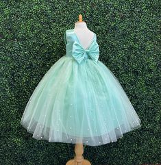 Our enchanting Ankle Length flower girl dresses are sure to turn heads! Bodice is made of Mint satin, waist consists of a matching sowed in sash (NOT DETACHABLE) The back of the dress has an open deep V-Back with a hidden zipper, followed by a detachable bow. The skirt has 4 Mint tulle layers for fullness, the top layer of tulle is ivory with ivory pearls. The dress has 2 layers of lining with crinoline. This dress is perfect for any occasion!  Dress Is Pictured with a petticoat NOT INCLUDED htt Green Princess Dress For Bridesmaids, Green Princess Dress With Bow, Spring First Communion Tulle Gown, Spring Princess Style First Communion Tulle Dress, Spring Princess Style First Communion Dress In Tulle, Princess Style First Communion Dress In Tulle For Spring, Spring Princess First Communion Dress For Pageant, Spring Princess Style First Communion Dress For Pageant, Princess Style First Communion Dress For Spring Pageant