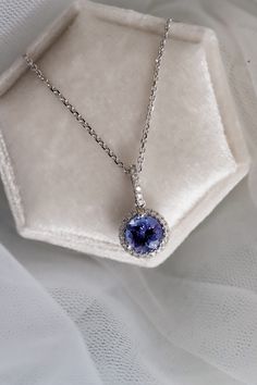 The beautiful purple color of the Tanzanite gemstone makes this necklace a true show-stopper.

We've set this 1.06ct Round cut Tanzanite in a White Gold pendant with a 0.14ctw Diamond Halo. Looking for a memorable birthday or anniversary gift? This bold pendant is perfect!

Gemstone: Tanzanite
Metal: 14K White Gold Chain, 18K White Gold Setting
Gem color: Purple
Weight: 1.06ct Tanzanite, 0.14ctw Diamond
Gem Cut: Round Brilliant Cut
Quality: 100% Natural Gemstone Sapphire Necklace With Brilliant Cut, Purple Diamond Wedding Necklace, Purple Diamond Necklace For Wedding, Purple Diamond Necklaces For Wedding, Brilliant Cut Tanzanite Gemstones, Sapphire Necklaces With Halo Setting, Elegant White Gold Tanzanite Necklaces, Formal White Gold Tanzanite Necklace, Elegant Tanzanite White Gold Necklace