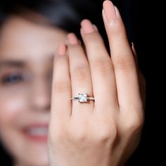 a close up of a person's hand with a diamond ring on their finger