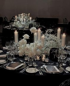 a black table with white flowers and candles