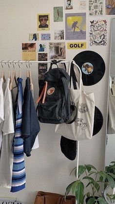 there are many bags hanging on the wall next to some pictures and clothes racks