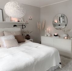 a bedroom with white furniture and candles on the nightstands in front of the bed