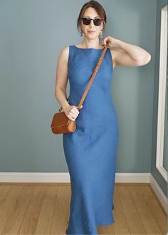 a woman in a blue dress holding a brown purse