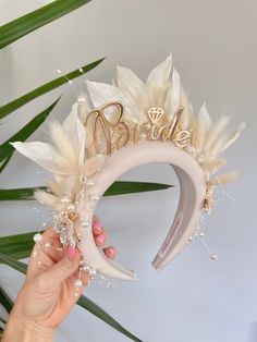 a woman holding up a bridal headband with feathers and pearls on it's side