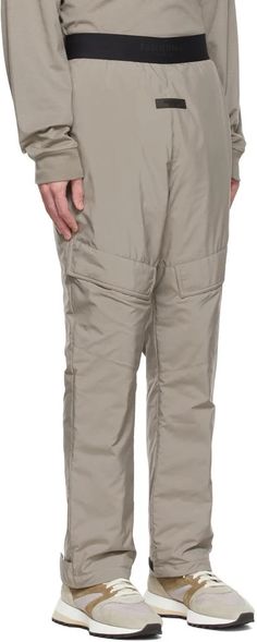 Fear of God ESSENTIALS.Taupe Polyester Cargo Pants.Insulated polyester satin cargo pants..· Logo bonded at elasticized waistband.· Rubberized logo patch at front.· Gusset at dropped inseam.· Flap pocket at legs.· Two-pocket styling.· Adjustable velcro tab at cuffs.· Fully lined.Please note that this item may not be shipped within the EU..Supplier color: Desert taupe.Body: 100% polyester. Fill: 100% polyester. Lining: 100% polyester..Made in China..221161M190043 Winter Utility Nylon Parachute Pants, Winter Utility Cargo Pants With Elastic Waistband, Winter Nylon Parachute Pants With Pockets, Winter Nylon Bottoms With Side Pockets, Utility Nylon Bottoms With Cargo Pockets, Solid Nylon Pants With Cargo Pockets, Full Length Nylon Cargo Pants With Elastic Waistband, Winter Nylon Pants With Pockets, Nylon Parachute Pants With Hip Pockets