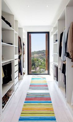 a hallway with white shelving and colorful rugs on the floor next to it