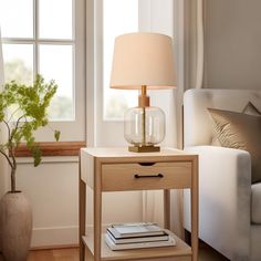 a small table with a lamp on it next to a white couch and window sill