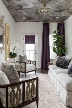 a living room filled with furniture and a painting on the ceiling above it's windows