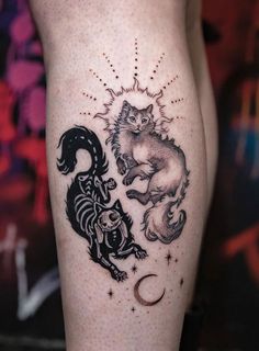 a tattoo on the leg of a woman with two cats and a moon in it