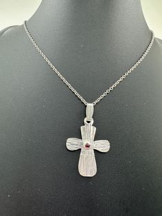 A Divine Fusion: Cross and Garnet Embrace the divine with our Argentium Silver Cross Pendant adorned with a small, precious Garnet. This pendant is a harmonious blend of faith and elegance, meticulously crafted to resonate with those seeking spiritual connection and refined style. The deep red hue of the Garnet beautifully complements the radiant silver, creating a captivating focal point. Key Features: Handcrafted with 925 Argentium Silver for enduring quality and shine. Small Garnet gemstone c Formal Spiritual Crucifix Jewelry, Spiritual Hammered Cross Necklace, Spiritual Cross Pendant Necklace For Formal Occasions, Spiritual Cross Necklace For Formal Occasions, Silver Cross Pendant, Spiritual Connection, Argentium Silver, Garnet Gemstone, Silver Cross