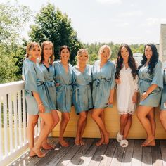 a group of women standing next to each other on top of a wooden deck wearing blue robes