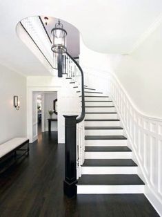 a white staircase with black and white striped flooring next to a light fixture on the wall