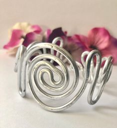 Gorgeous adjustable aluminum bracelet with intertwining spirals. Elegant, charming, bold and, beautifully hand-crafted. ♥ Lightweight  and easy to wear ♥ Stunning AND Bold ♥ This bracelet can be dressed up or down ♥ Molds to fit any wrist size ♥ Custom made to order - one-of-a-kind ♥ Made out of aluminum wire  ♥ Non-tarnishing and hypo-allergenic. This item is made by hand one at a time so there may be slight variations with each design.  This bracelet is made with aluminum so it will bend so you can get the correct size but won't keep bending while on your wrist. To care for your bracelet, remove the cuff before using soaps and cleaning products is recommended to extend the life of, and keep your jewelry looking new. Thanks for visiting my shop! I specialize in wire wrapping jewelry made Spiral Silver Cuff Bracelet, Silver Spiral Metal Cuff Bracelet, Silver Spiral Cuff Bracelet Gift, Adjustable Metal Spiral Cuff Bracelet, Adjustable Spiral Silver Cuff Bracelet, Adjustable Silver Spiral Cuff Bracelet, Spiral Metal Cuff Bracelet As Gift, Silver Spiral Bohemian Bracelets, African Beaded Bracelets