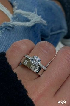 a woman's hand with a diamond ring on her left hand and the other hand holding an engagement ring