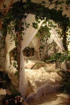 a canopy bed covered in white curtains and greenery