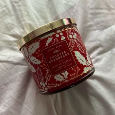 a candle that is sitting on top of a white sheet with red and gold designs