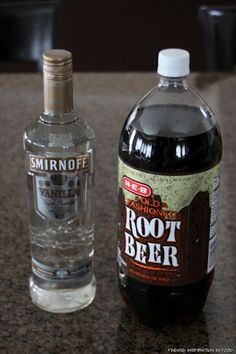 a bottle of root beer next to an empty glass bottle