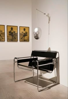 a black chair sitting in front of two pictures on the wall next to a lamp