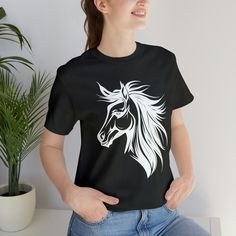 a woman wearing a black t - shirt with a white horse on it