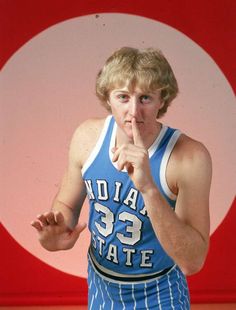 a young man wearing a blue and white basketball uniform holding his finger to his mouth