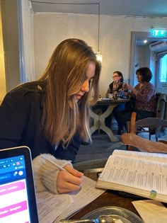 a woman sitting at a table writing on paper