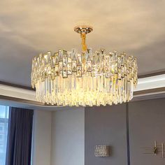 a chandelier hanging from the ceiling in a room with grey walls and curtains