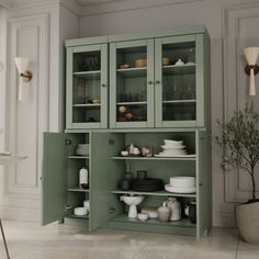 a green cabinet with glass doors is in the middle of a white dining room area