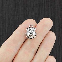 a person's hand with a small dog charm in the shape of a crown