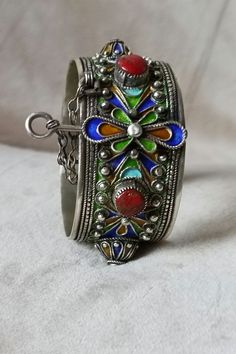 An elegant bracelet that symbolizes the Moroccan Amazigh culture. It can be worn on all occasions. It is made of silver and decorated with colorful patterns and red stones. Berber Amazigh hinged cuff bracelet in silver and enamel - Morocco - Inner diameter: 6 cm - Total weight: 72.4 grams If you have any questions about this item, please feel free to contact me. I will be happy to respond as soon as possible. Visit my shop: yourarticles Artisan Bangle As Festival Gift, Artisan Bangle For Festivals As A Gift, Artisan Bangle For Festivals And Gifts, Artisan Bangle As Gift For Festivals, Artisan Bangle As A Gift For Festivals, Unique Sterling Silver Bracelets For Ceremonial Occasions, Silver Beaded Bangle Bracelets For Festivals, Artisan Cuff Bracelet As Festival Gift, Ceremonial Sterling Silver Bracelets