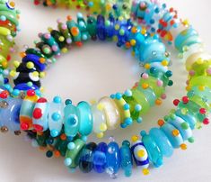 multicolored bracelets are arranged on a white tablecloth with beads and glass beads