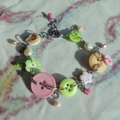 a close up of a bracelet on a bed with buttons and other things attached to it