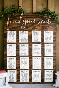 a seating chart for a wedding with greenery on the wall and wooden planks