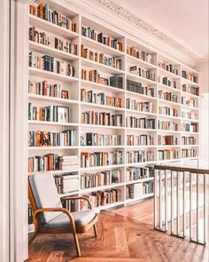 a chair sitting in front of a bookshelf filled with lots of bookcases