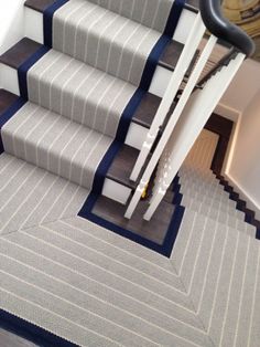 an image of stairs with carpet and rugs on the bottom, next to a stair case