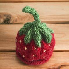 a knitted strawberry sitting on top of a wooden table