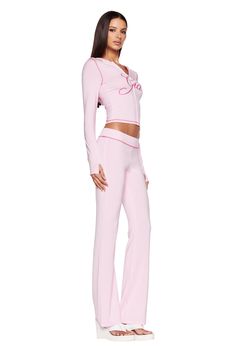 A woman stands posing in a full-length, side view. She is wearing a light pink, long-sleeved top with J'Adore written on it and matching pastel pink BLARE TRACKPANT from I.AM.GIA. She has long, straight hair and is wearing white, open-toe platform sandals. I Am Gia Pink Set, Wonyoungism Black Woman, Pink Iamgia Set, Pink Sets Outfit, Streetwear Fashion Pink, 2 Piece Lounge Set Outfit, Cute Sets Two Pieces, Outfits With Pink Pants, Pink Set Outfit