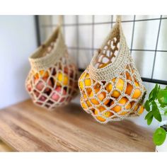 two bags filled with oranges sitting on top of a wooden table next to a potted plant