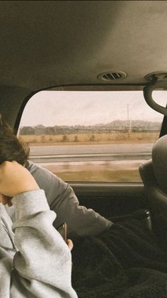 a woman sitting in the back seat of a car with her hand on her head