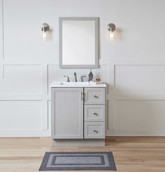 a bathroom vanity with a mirror above it and a rug on the floor next to it