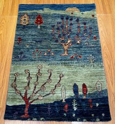 a blue rug with trees and flowers on the floor in front of a wooden floor