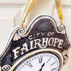 a clock hanging from the side of a door that says city of fair hope on it