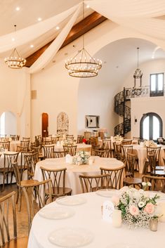 a room filled with tables and chairs covered in white tablecloths