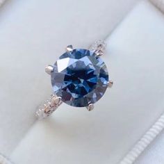 a blue diamond ring sitting on top of a white box