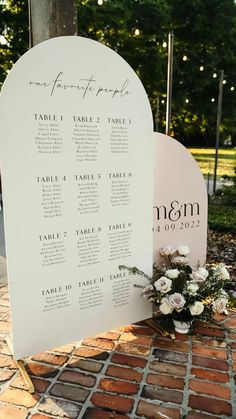 a table plan is set up on the side of a brick walkway with flowers and greenery