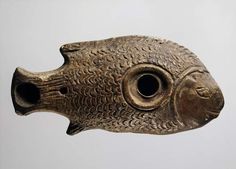 an old bronze fish head with holes in it's mouth, on a white background