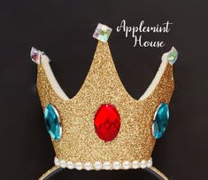 a gold crown with blue and red stones on it's side, against a black background