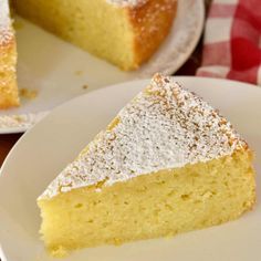 a piece of cake on a plate with powdered sugar on top and another slice in the background