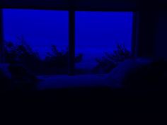 a bed sitting next to a window in a room with blue light coming from it